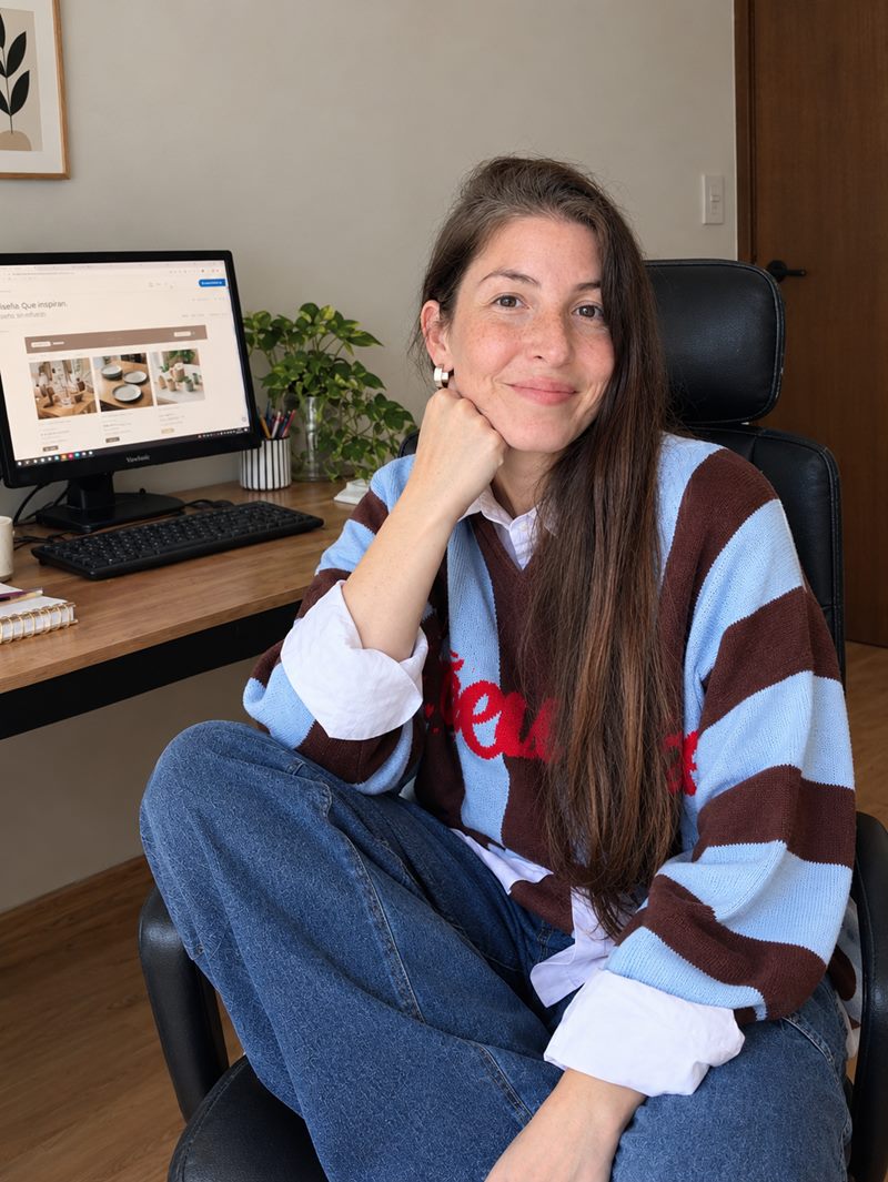Dama sonriendo en su escritorio, con una tienda online abierta en la pantalla